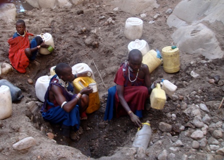 Maasai ladies collecting dirty water from a dry riverbed one cup at a time.